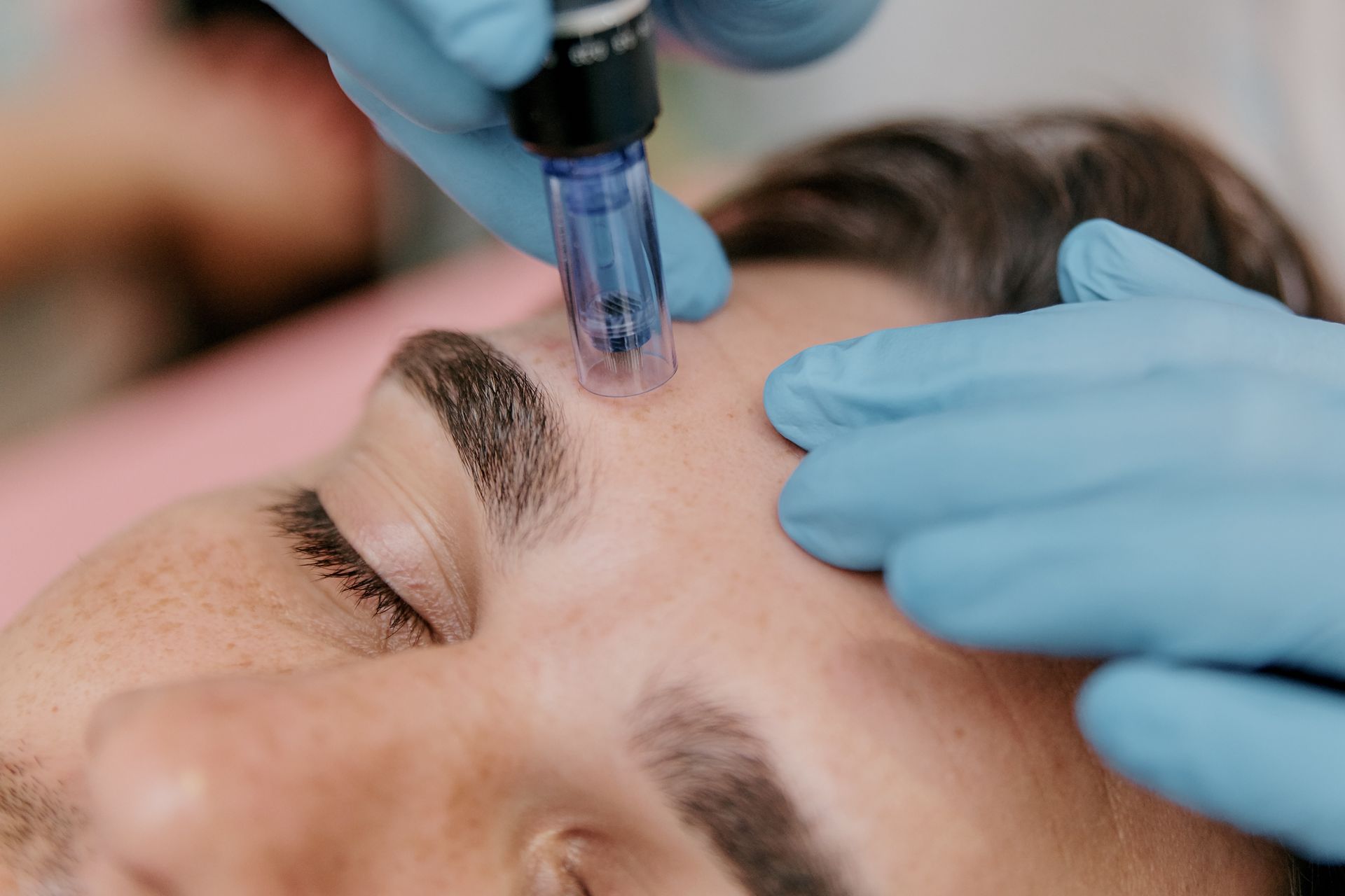 A man is getting a facial treatment with a machine on his face.
