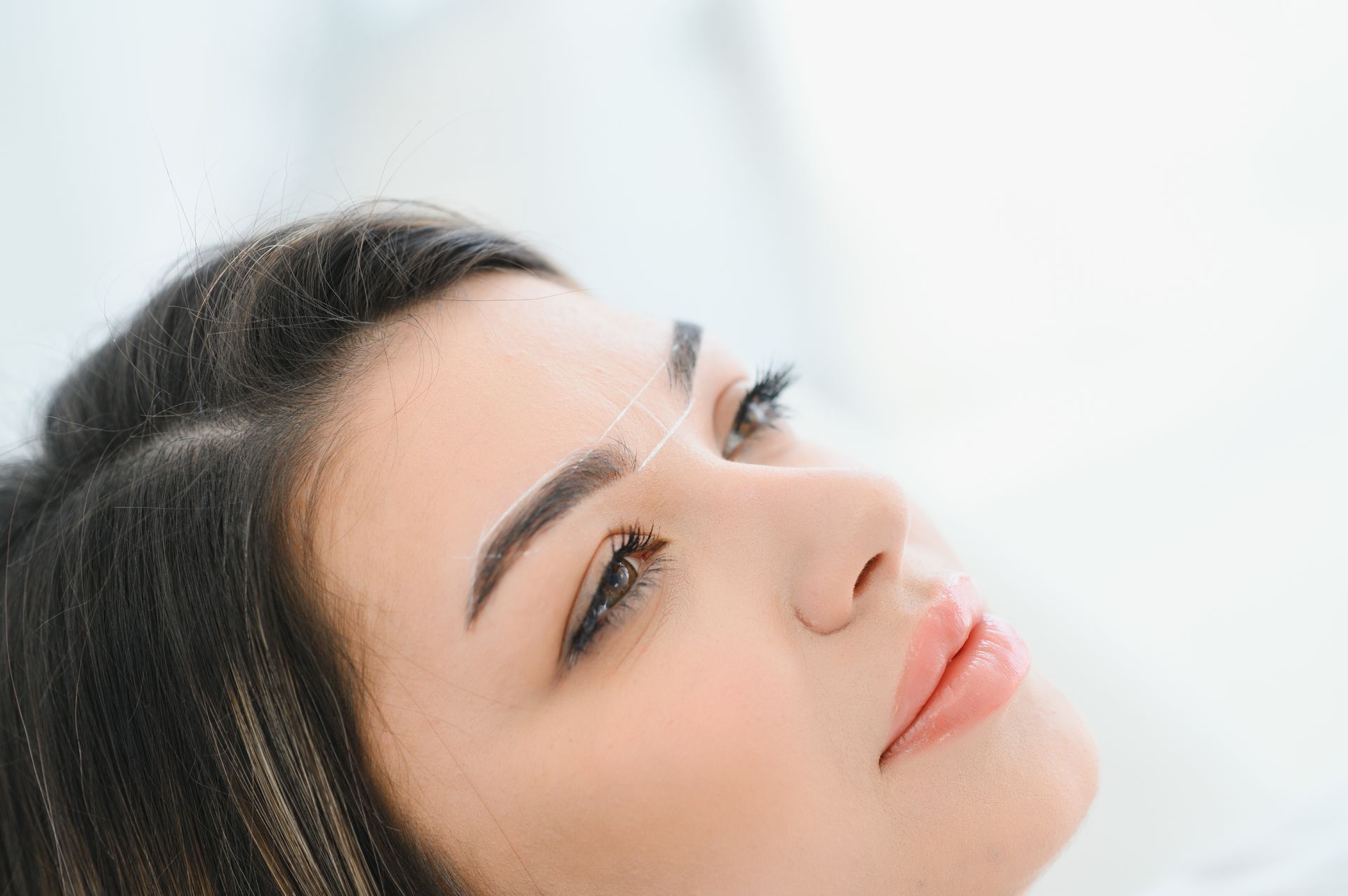 A close up of a woman 's face with a needle in her eyebrow.