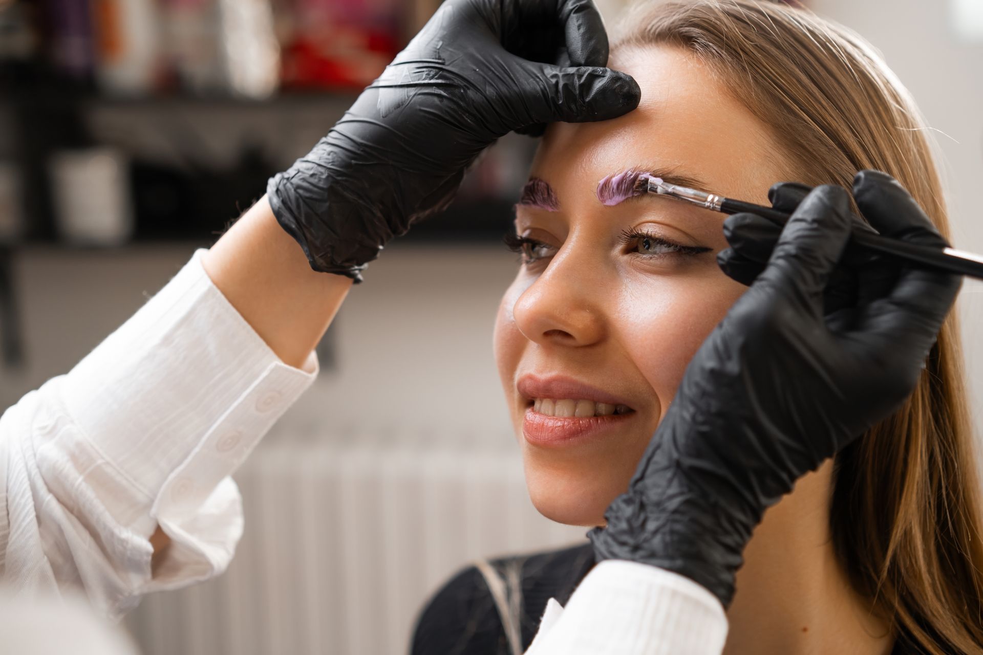 A woman is getting her eyebrows dyed in a salon.