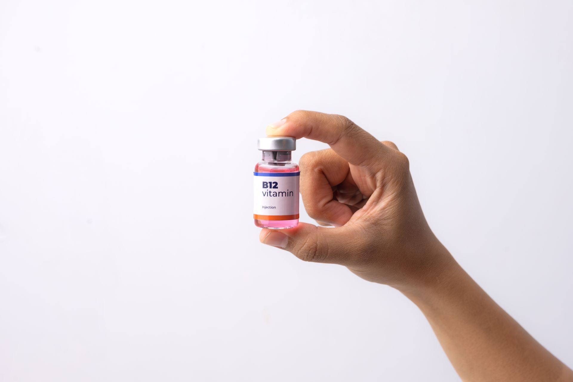 Hand holding a small pink medicine vial against a white background