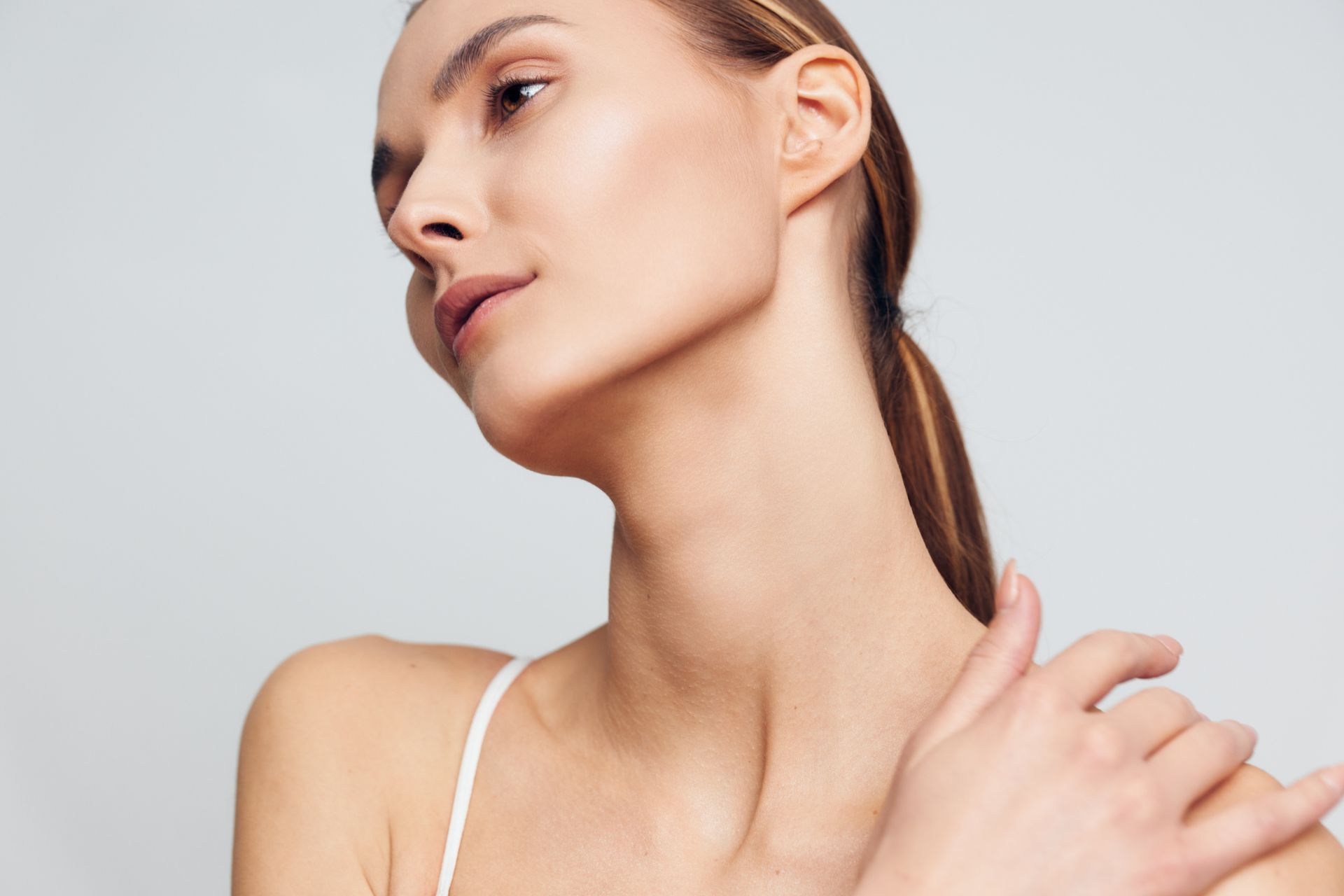 Woman touching her shoulder in a minimalist studio portrait