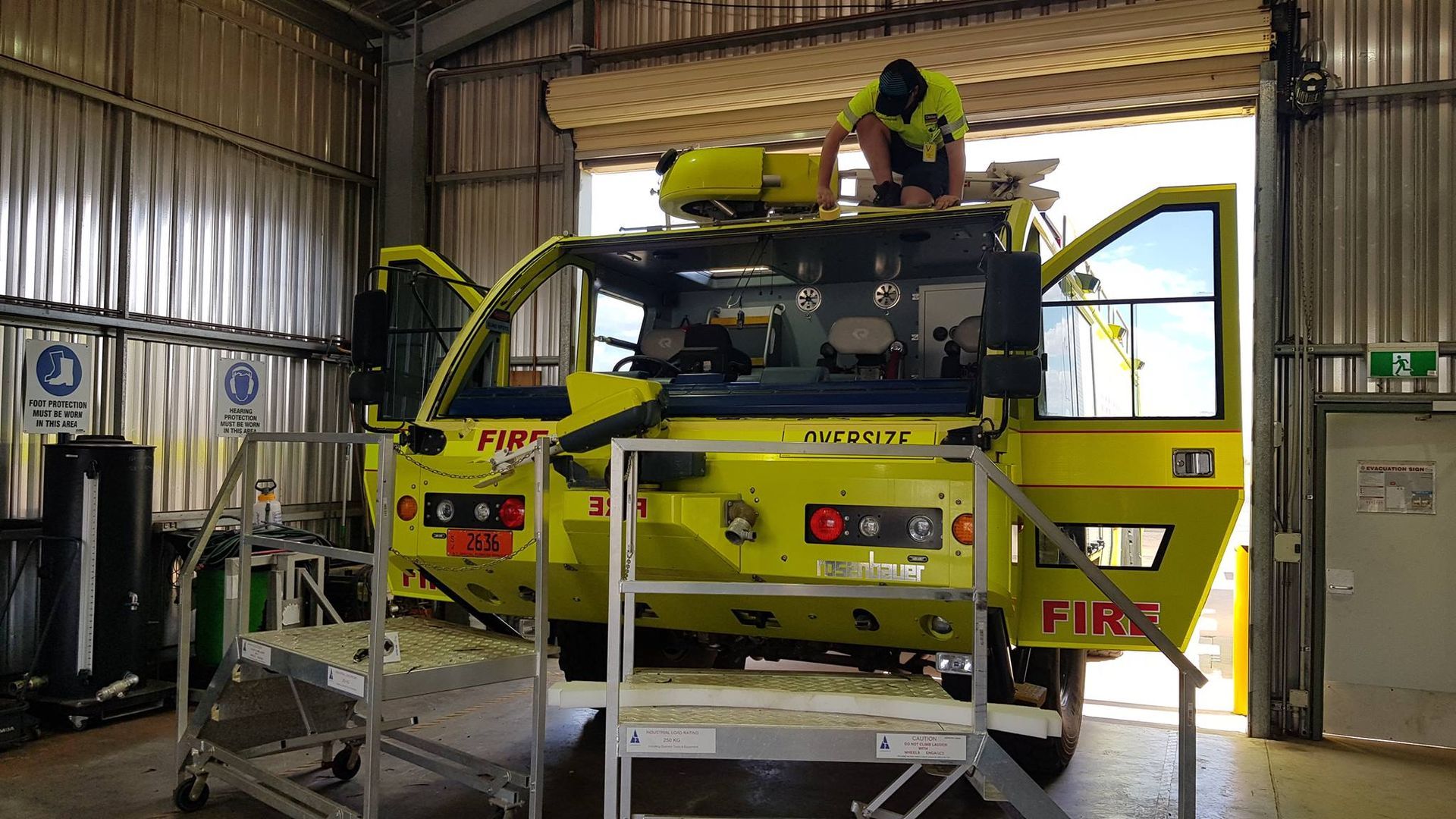 A Man is Working on a Yellow Fire Truck in a Garage — Trusty Glass In Alice Springs, NT