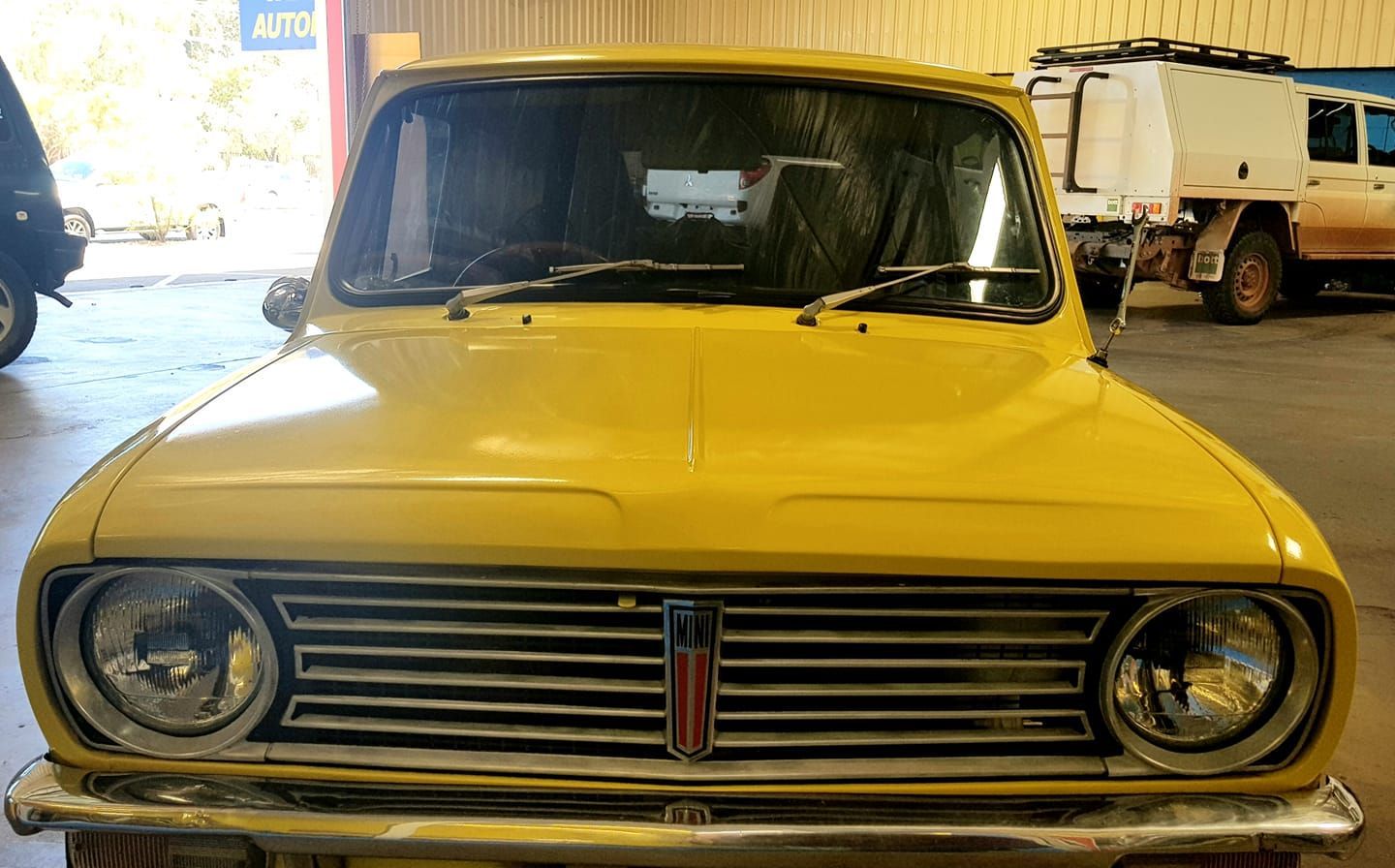 A Yellow Car is Parked in a Garage Next to a Truck — Trusty Glass In Alice Springs, NT