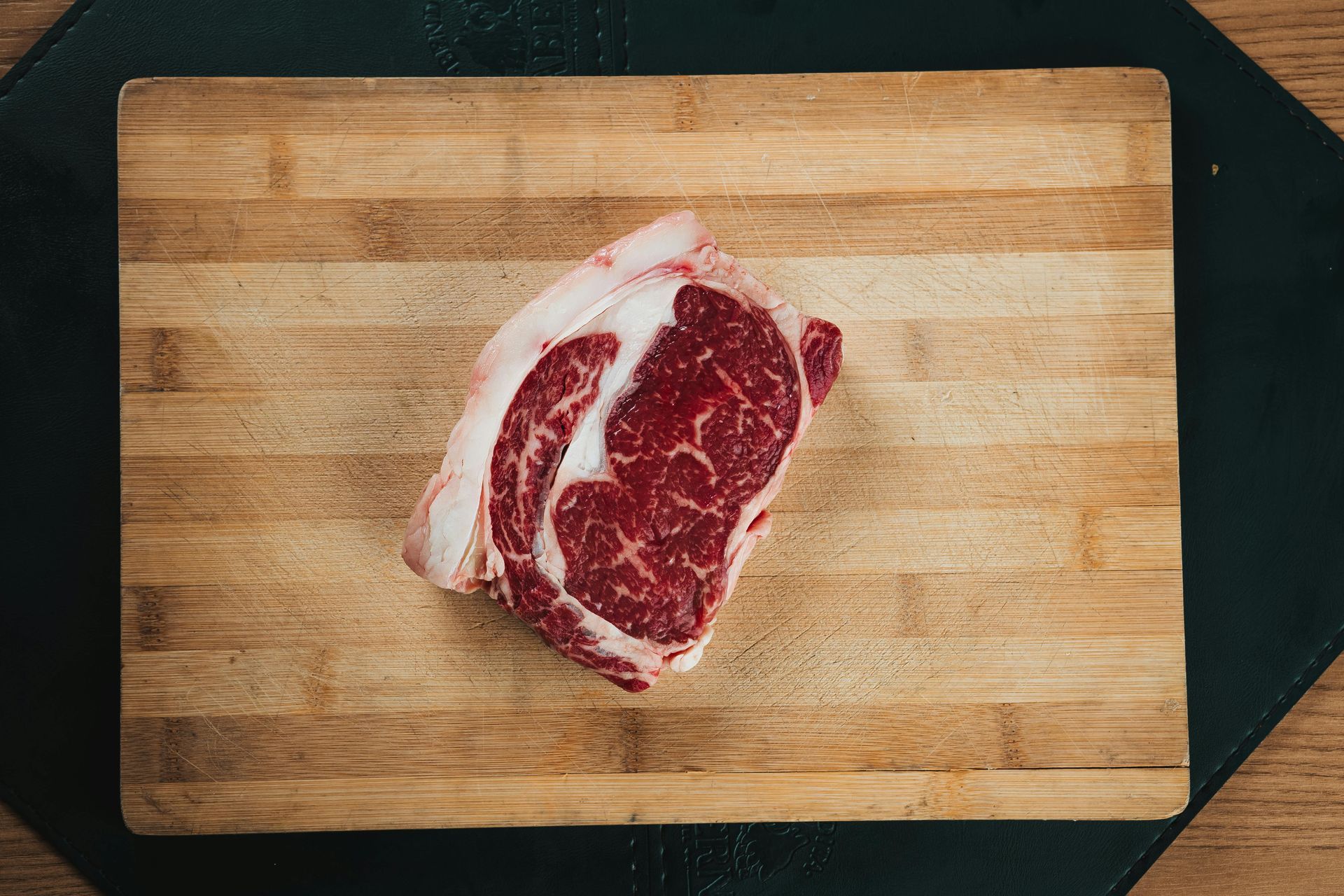Raw marbled steak on a wooden cutting board