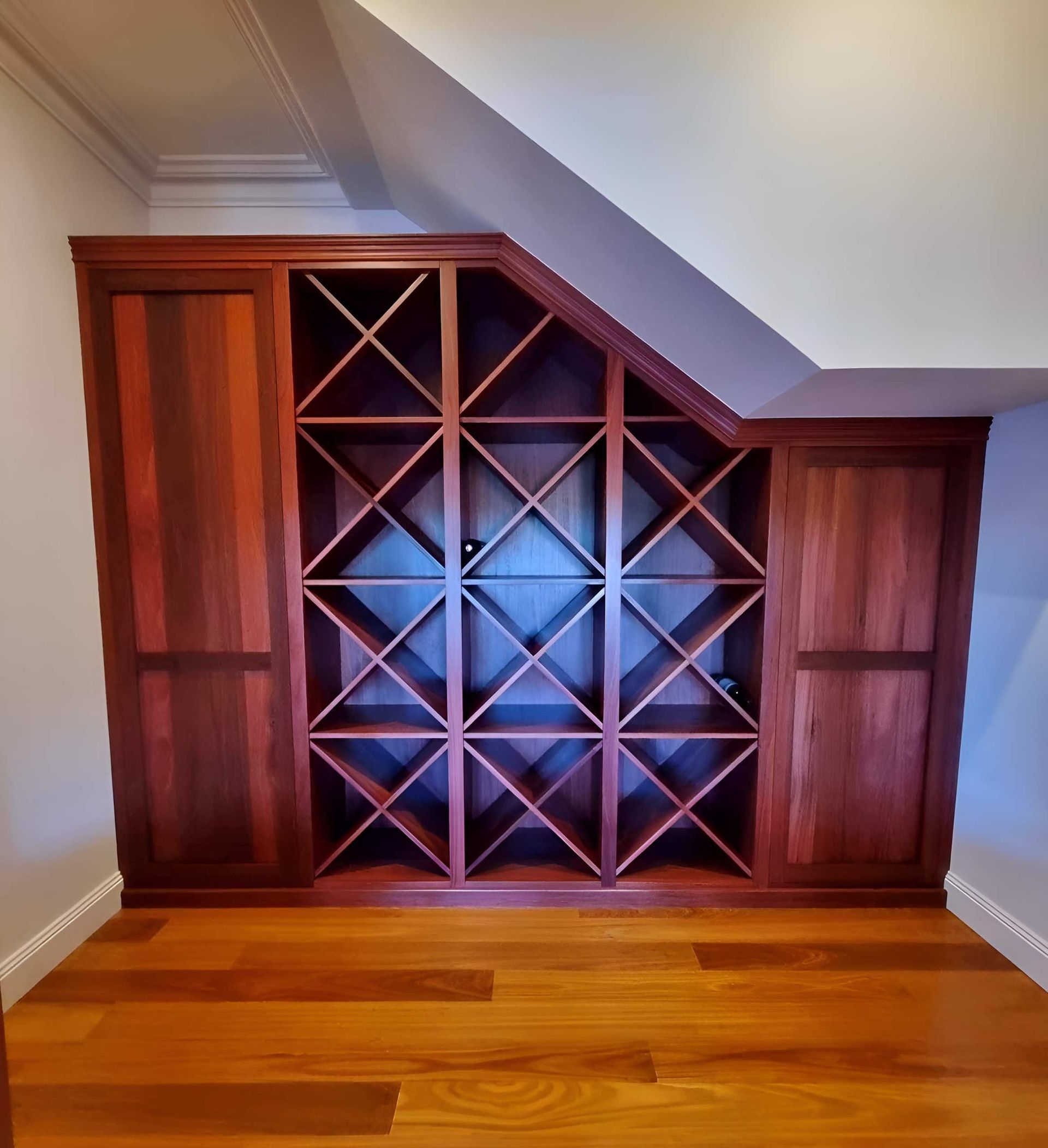 A room with a wooden wine rack under a staircase— Envisage Furniture in Kialla, VIC