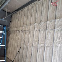A large wall covered in foam insulation with a ladder in the background.