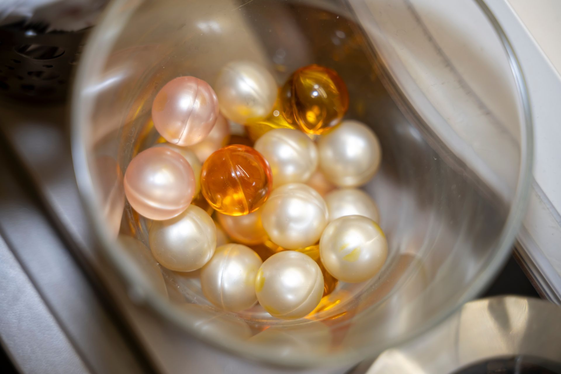 Un bol en verre rempli de perles et de boules orange.