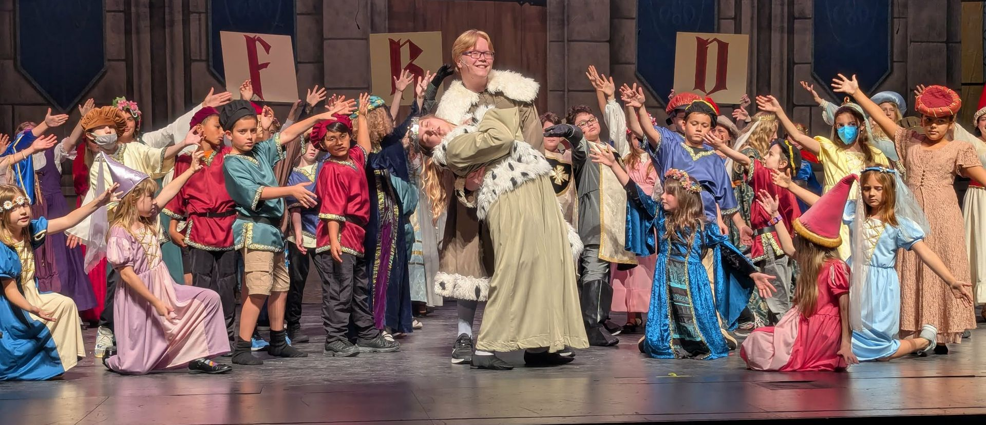 Stage production of SpongeBob characters: pirate, SpongeBob, other characters, all smiling. Bright colors, stage setting.