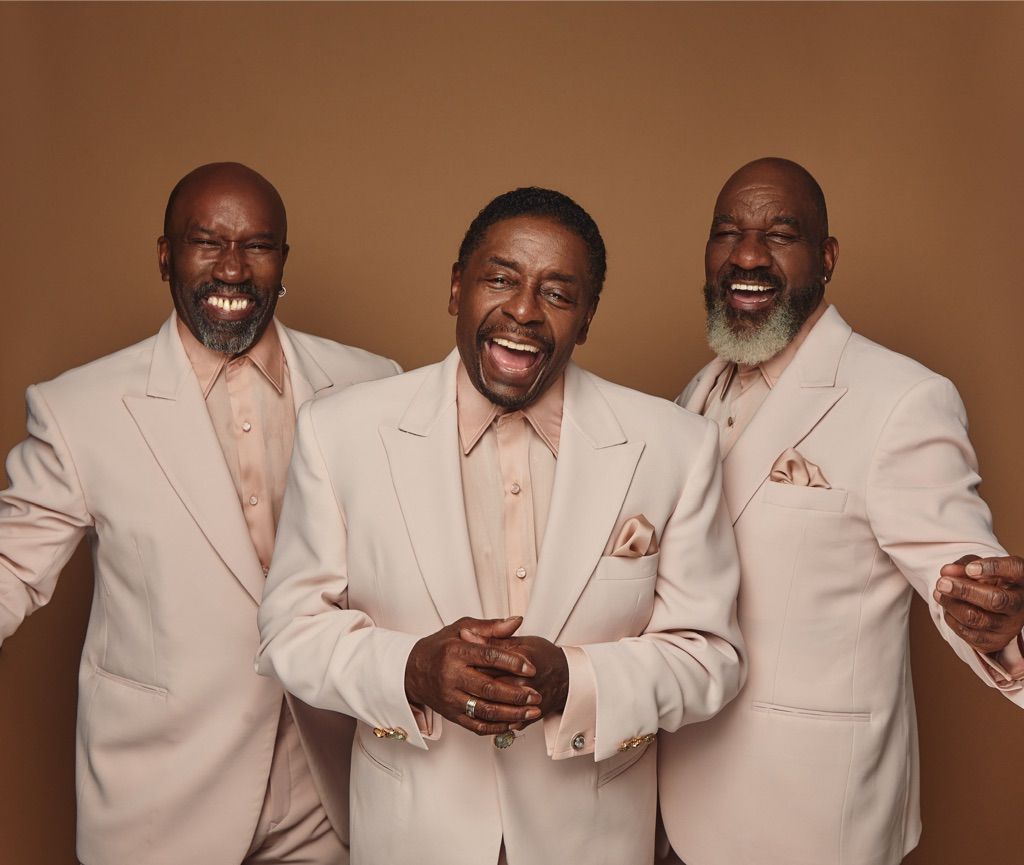 Chairmen of the Board: Three men singing with mics, stage lights behind them, colorful floral suit jackets.