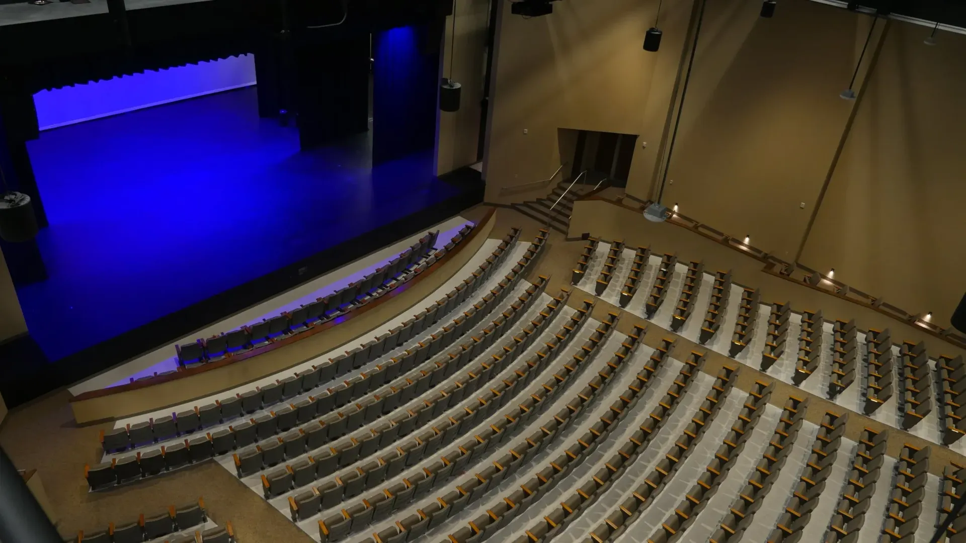 An auditorium with rows of seating facing a blue-lit stage.