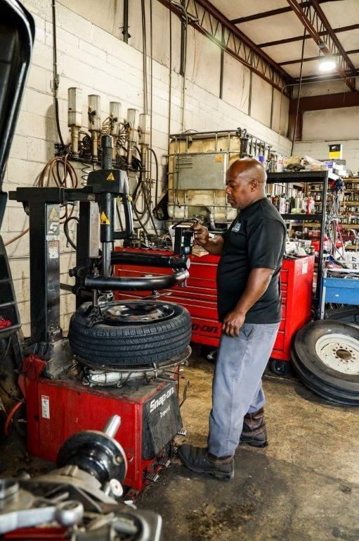 a man is standing next to a tire changer in a garage .