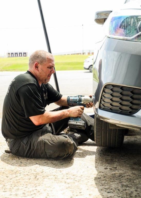 a man is kneeling on the ground working on a car