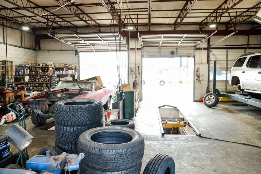a stack of tires sits in a garage next to a car