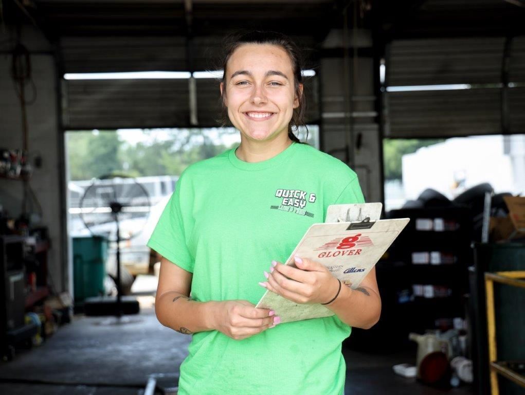 a woman wearing a green quick 's easy shirt holds a clipboard