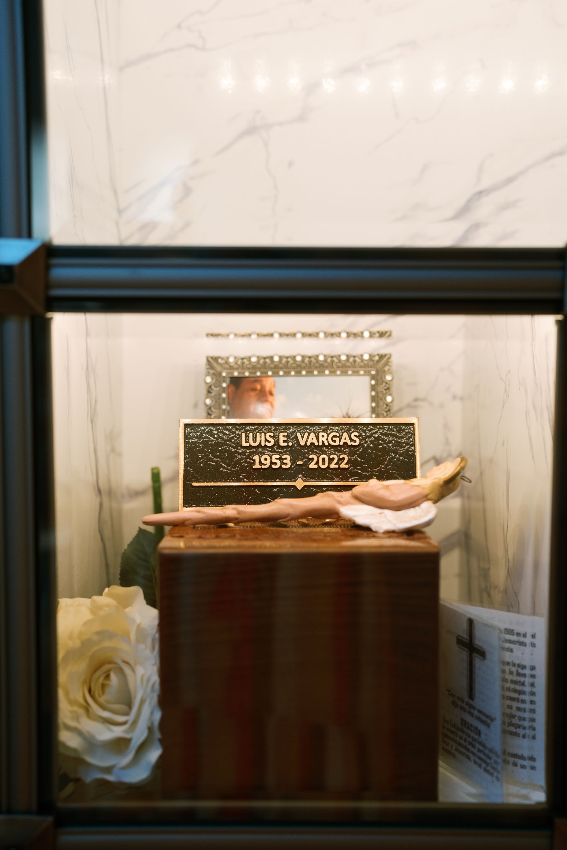 An urn niche containing a wooden urn, a nameplate for