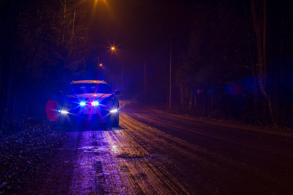 A Police Car is Driving Down a Snowy Road at Night — Cairns Criminal Lawyers In Cairns City, QLD