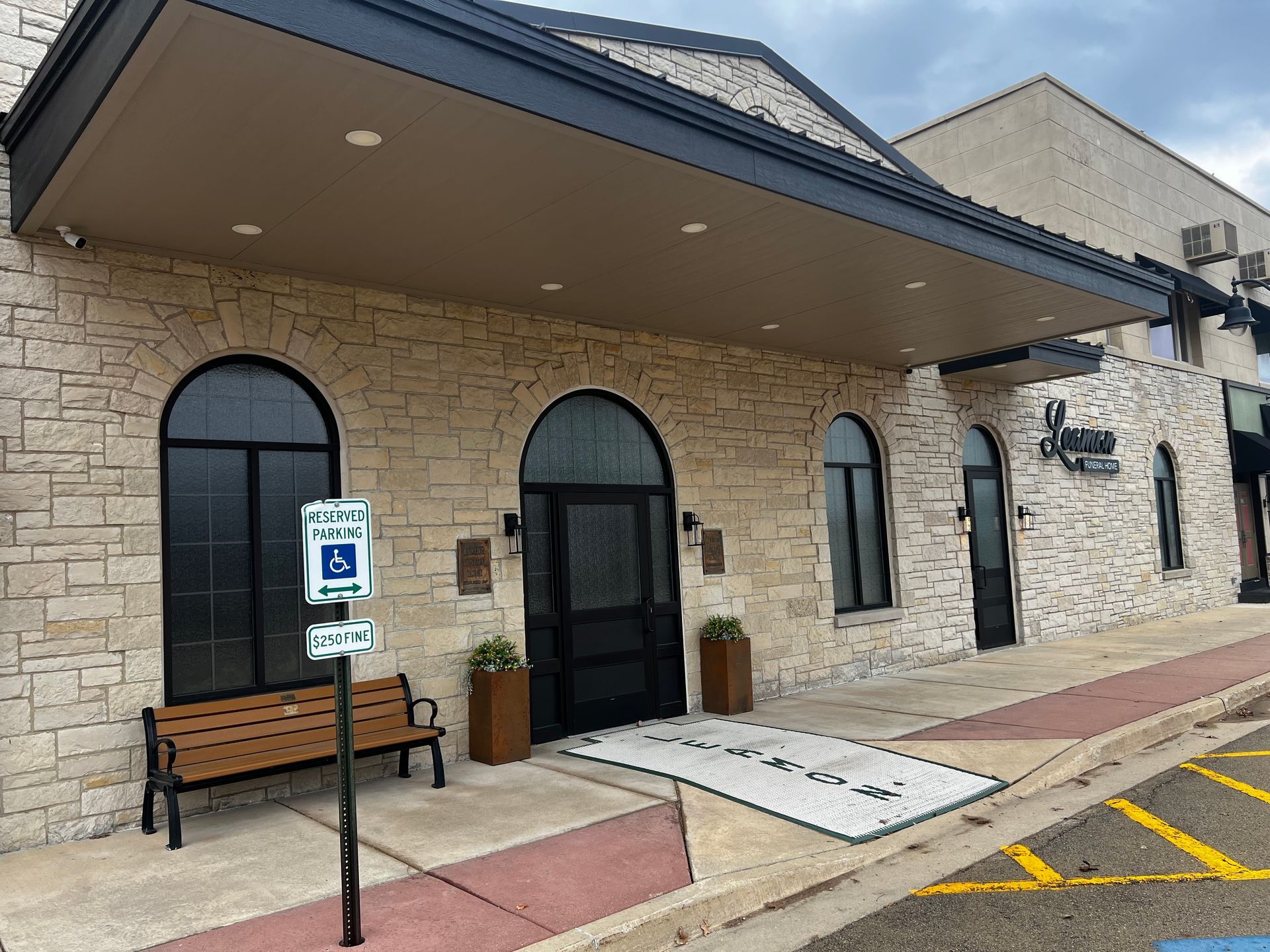 Exterior of a building with arched windows and doorway, light stone facade, and holiday decorations.