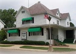 White two-story building with green awnings. 