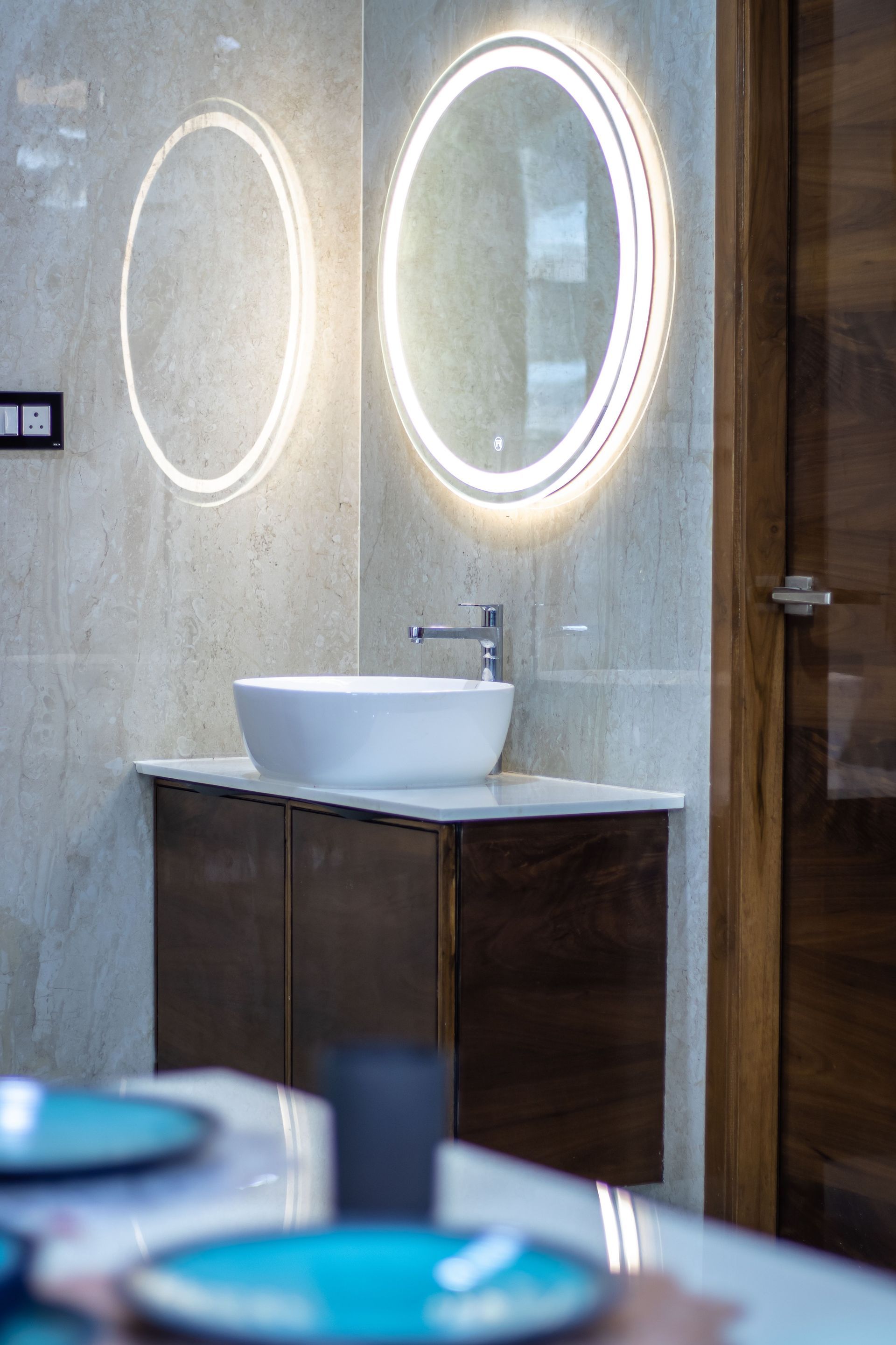 Modern bathroom remodel with oval backlit mirrors, a white vessel sink, and a dark wood vanity.