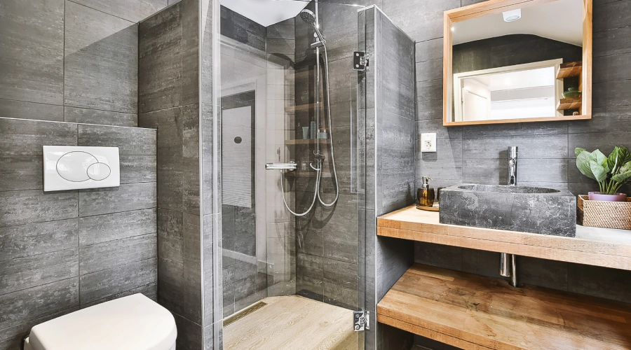 Modern gray-tiled bathroom with glass shower, floating vanity, mirror cabinet, and toilet