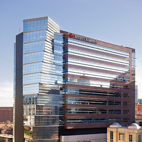 Modern glass office building with reflective windows and a rooftop sign under a clear sky
