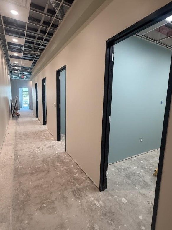 Interior hallway of a building under construction with open doorways and unfinished floors