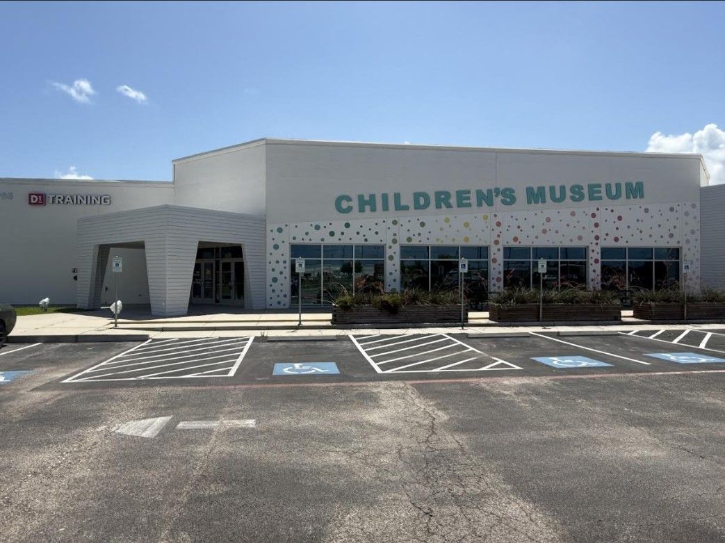 Children’s Museum building exterior with parking lot under a clear blue sky