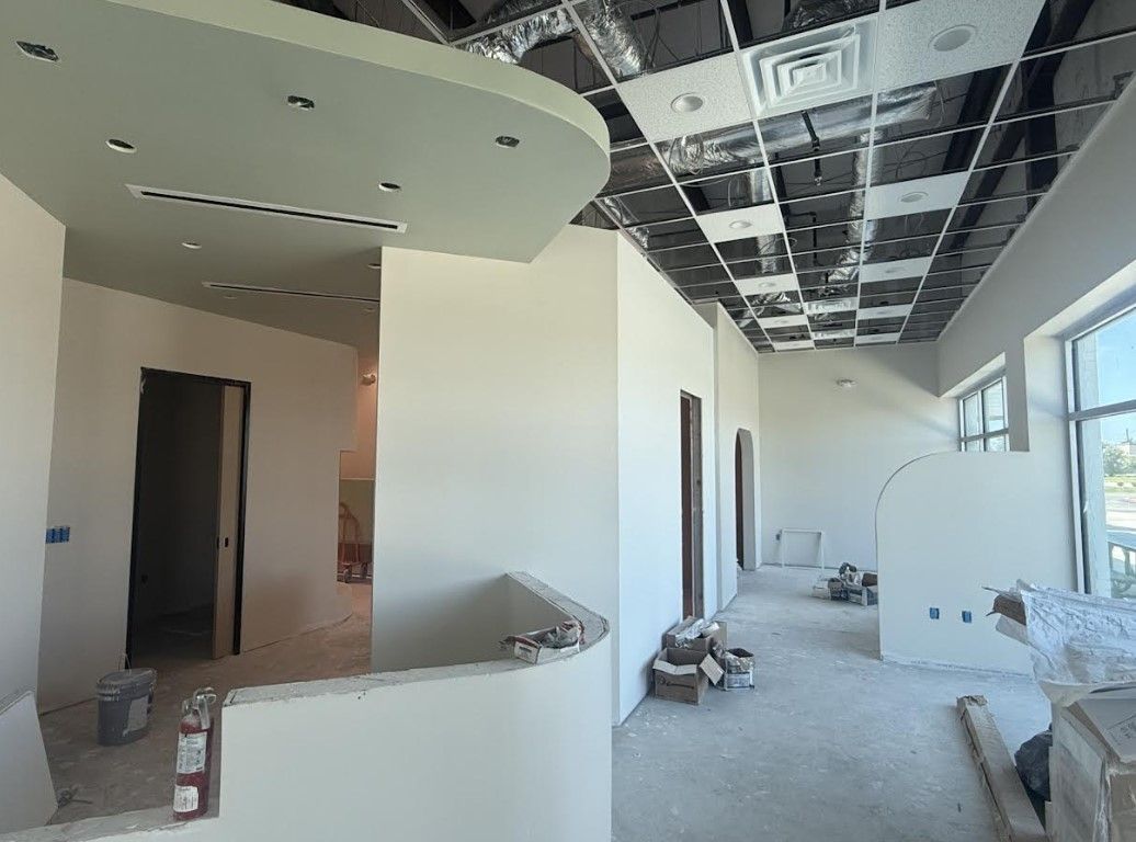 Partially renovated interior room with exposed ceiling, white walls, and construction materials on the floor