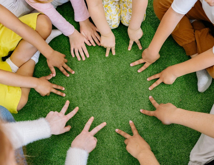 Hands pointing inward in a circle on green grass