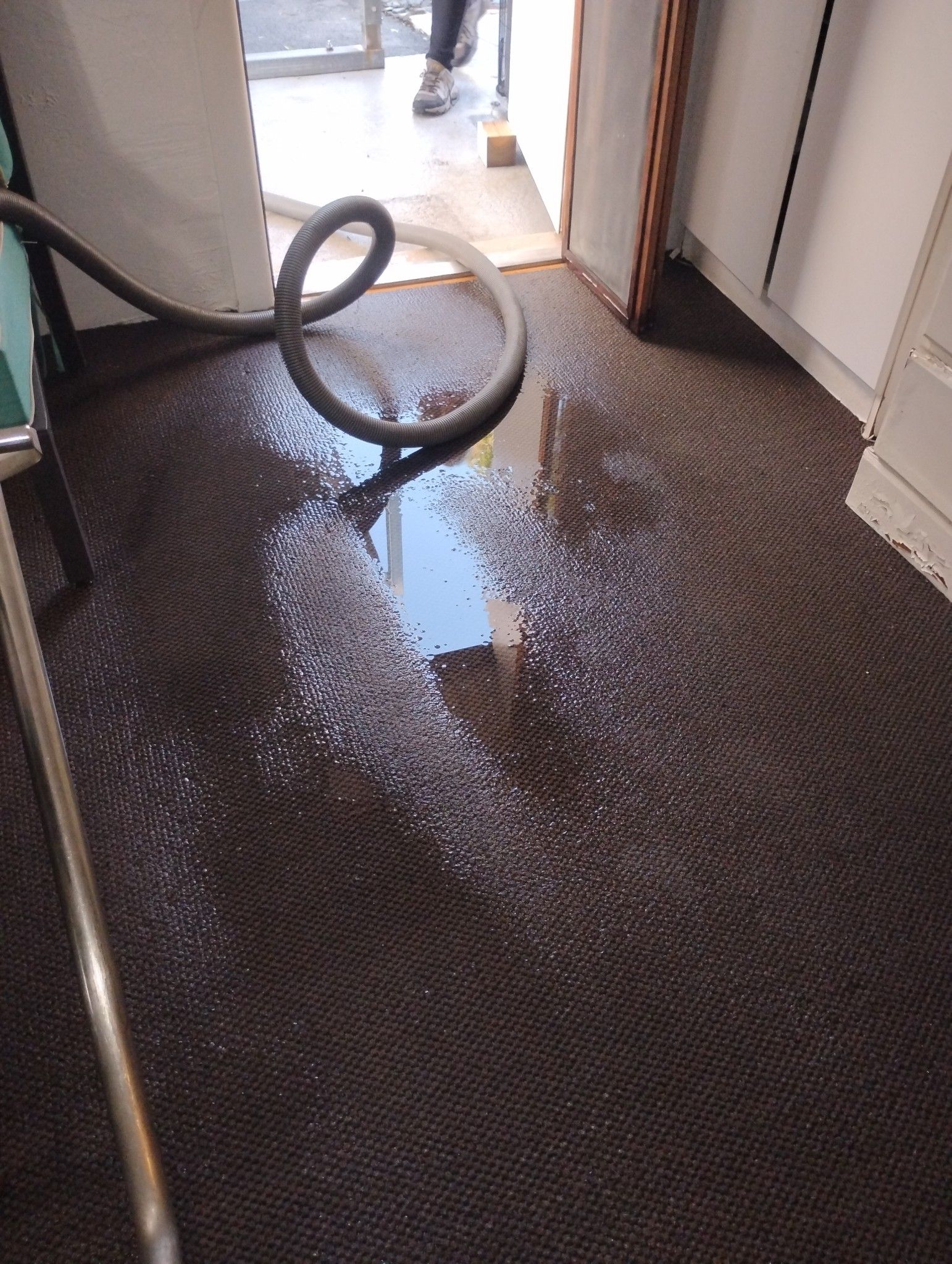 A vacuum cleaner is cleaning a flooded floor with a hose.