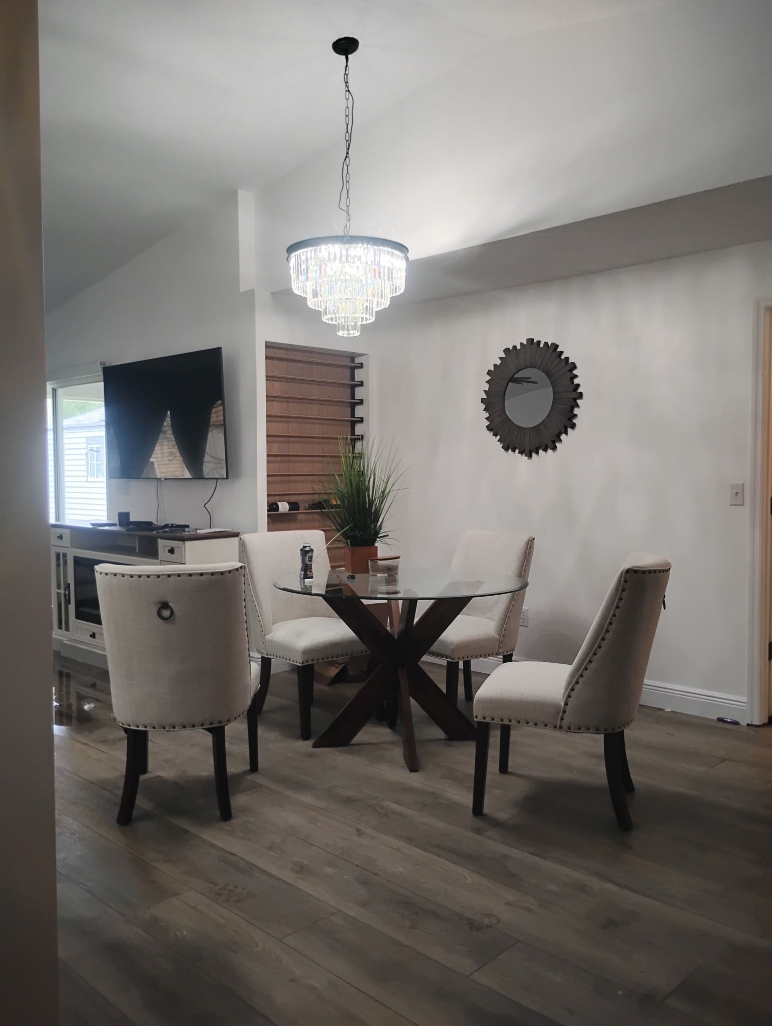 Dining room with table, chairs, chandelier, and a decorative mirror on the wall.