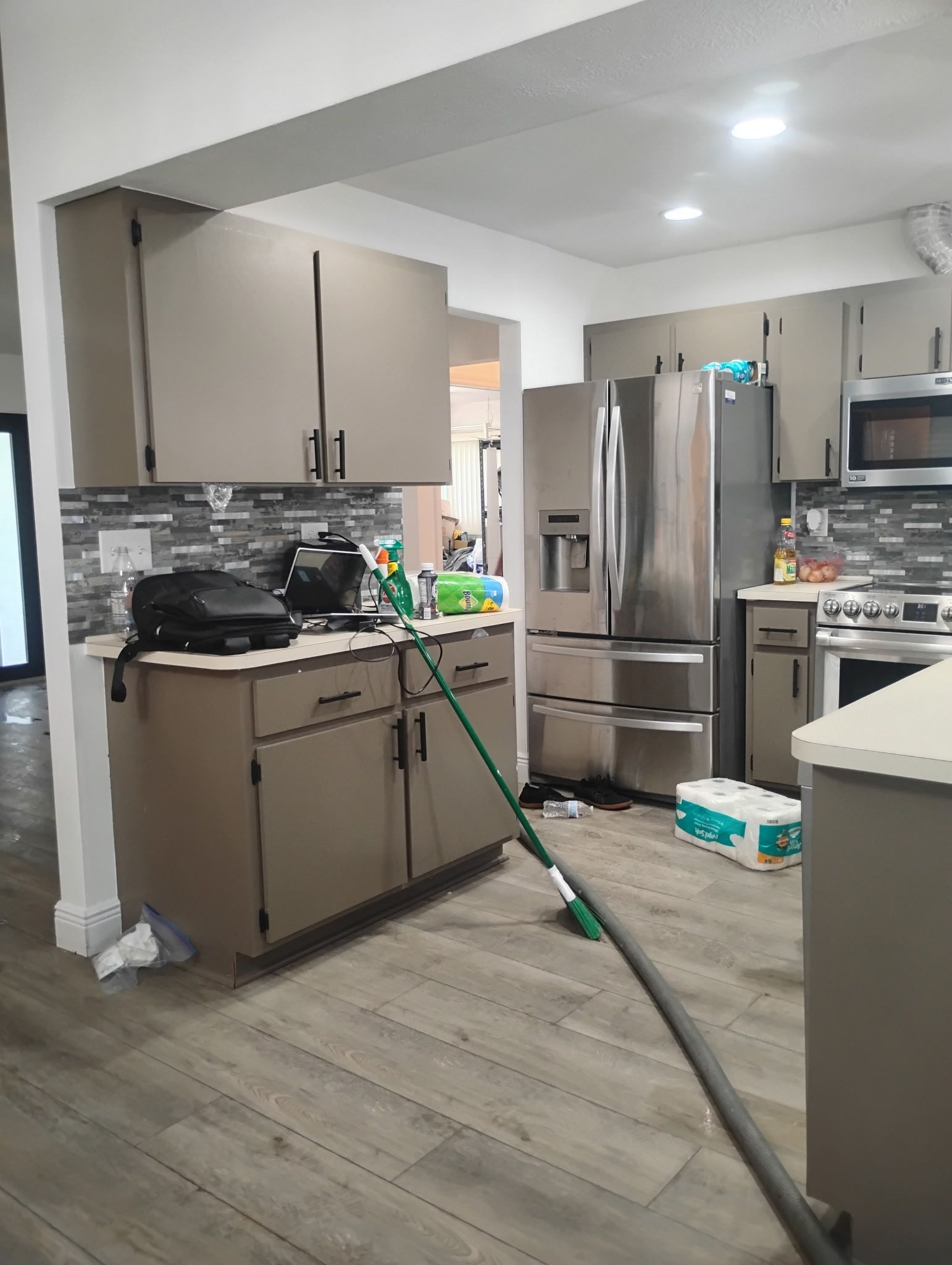 Kitchen with taupe cabinets, stainless steel appliances, and gray tile backsplash.