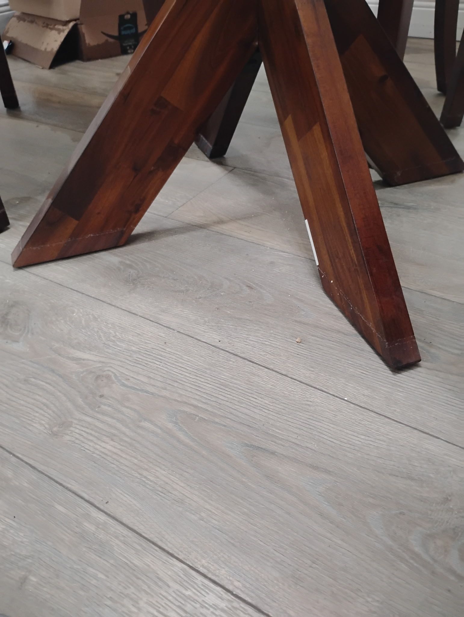 Wooden table legs on light grey wood flooring.