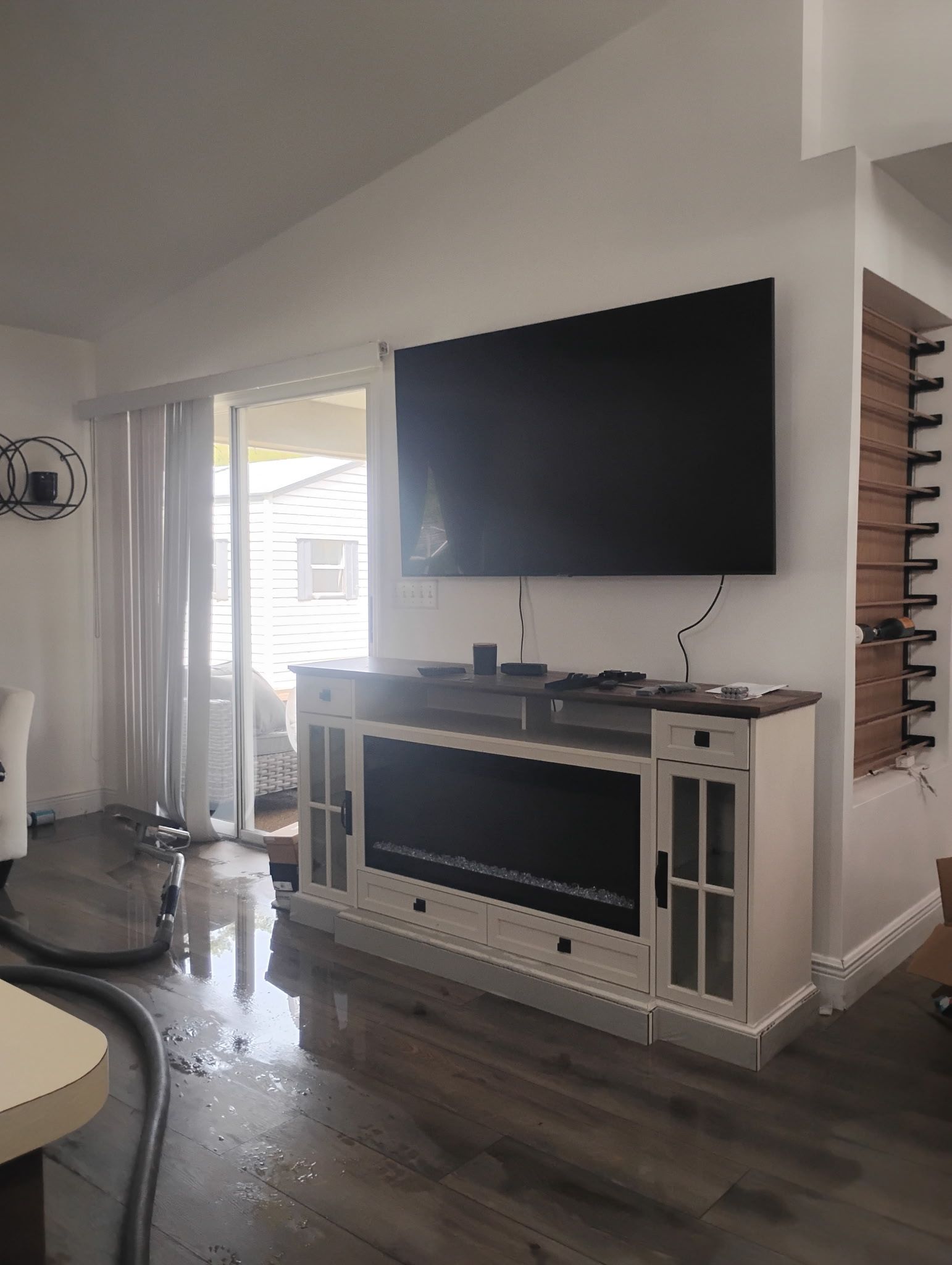 A living room with a TV, fireplace console, and sliding door. Water on the floor.
