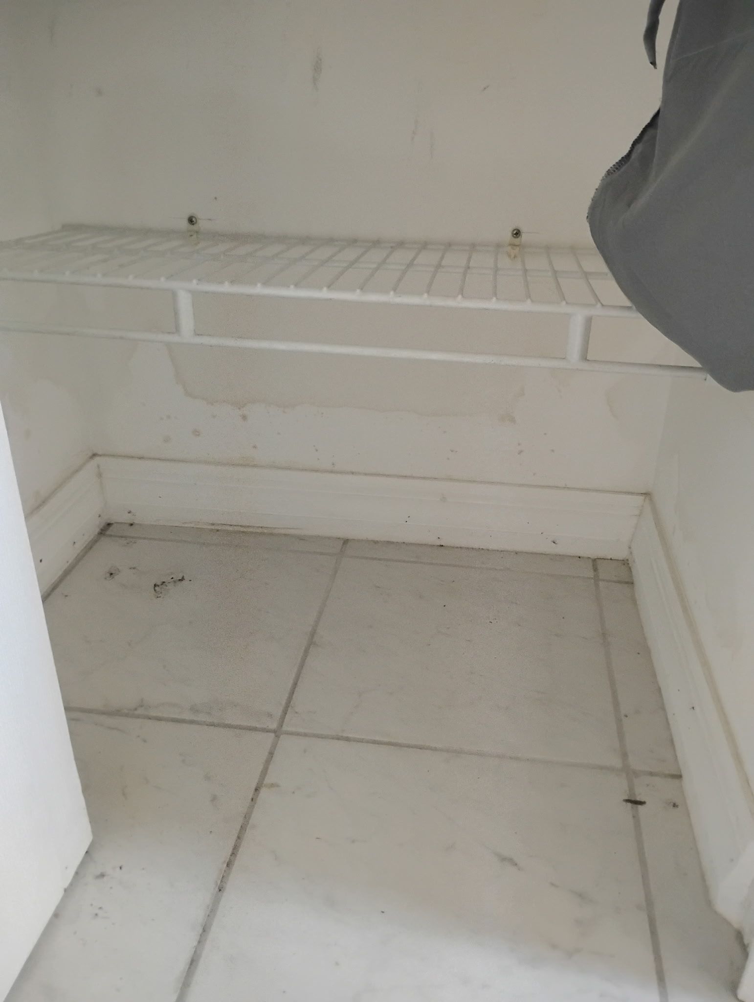 White wire shelf above tiled floor in a closet; light gray walls.