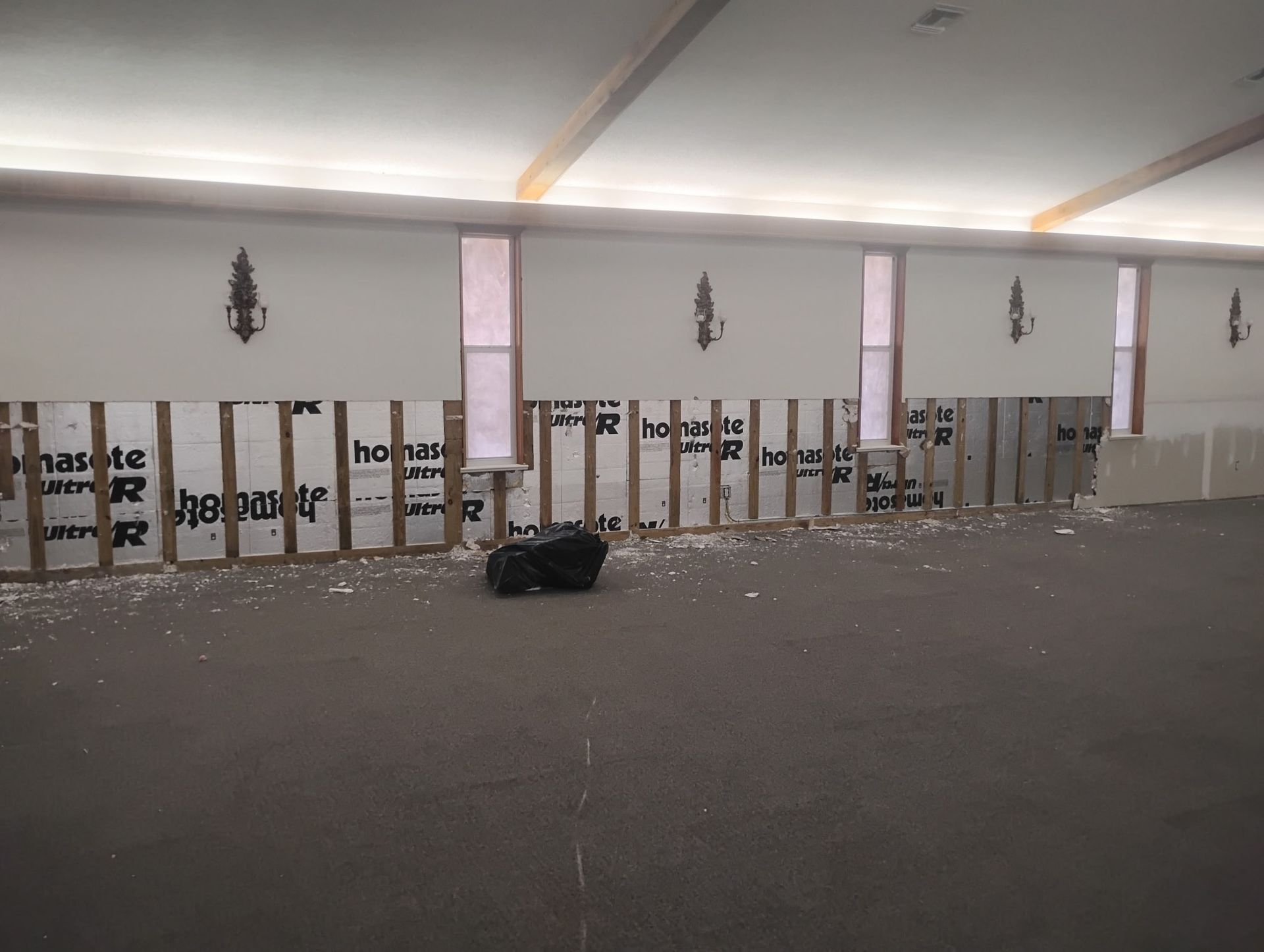 Interior view of a room under construction, with exposed wooden studs, insulation, and partially finished walls.