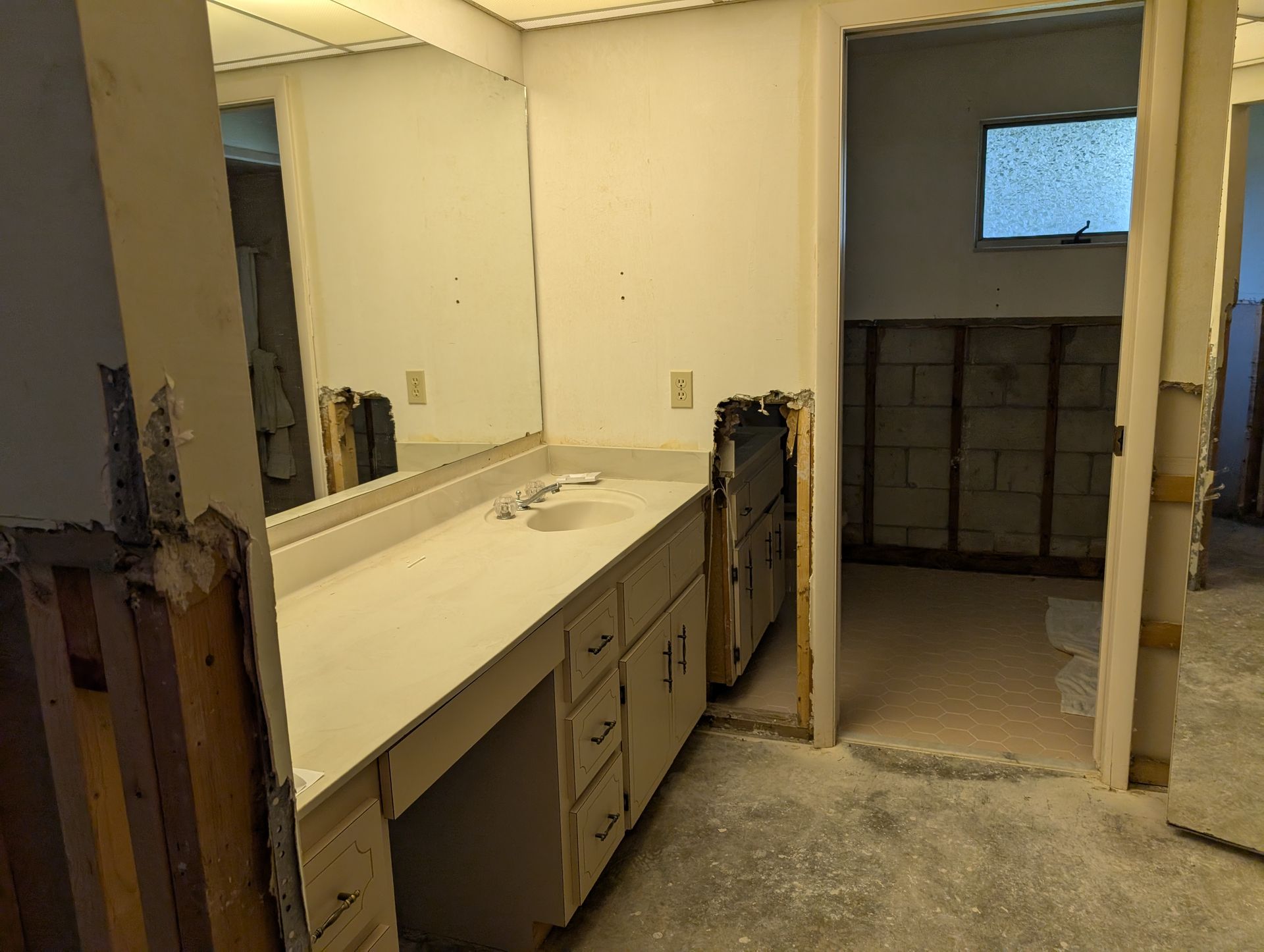 Bathroom under renovation with vanity, mirror, and exposed walls.