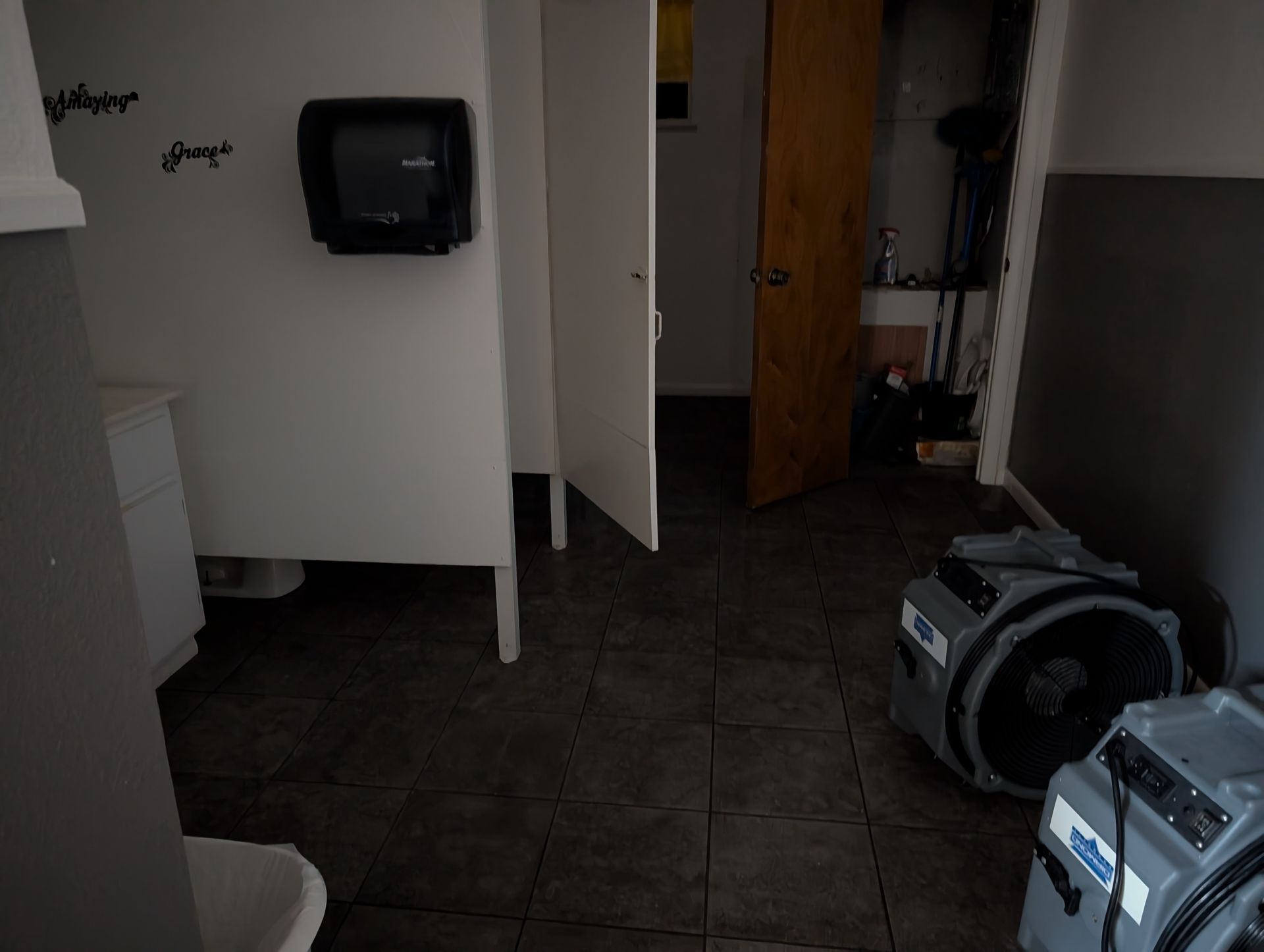 Bathroom interior with door open, dark gray floor, drying equipment.