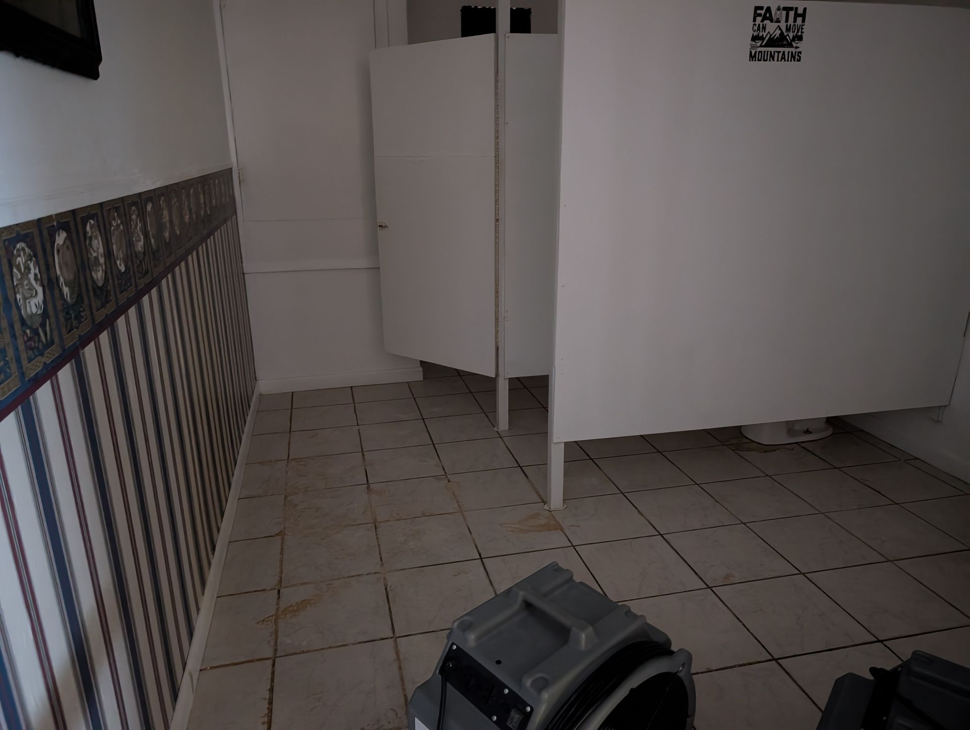 Public restroom with tile floor and white stalls.
