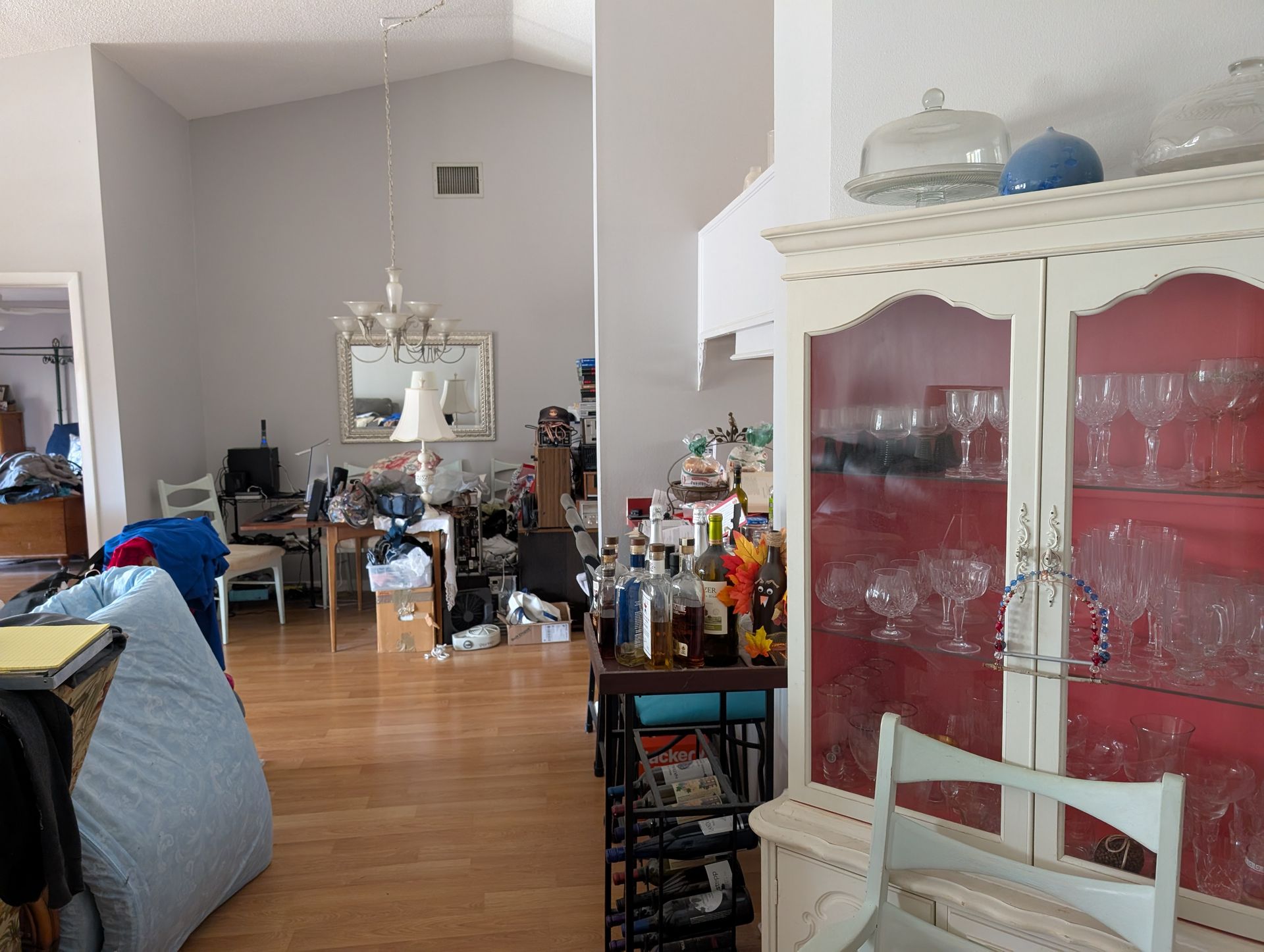 Living room with cluttered furniture, a china cabinet, and hardwood floors.
