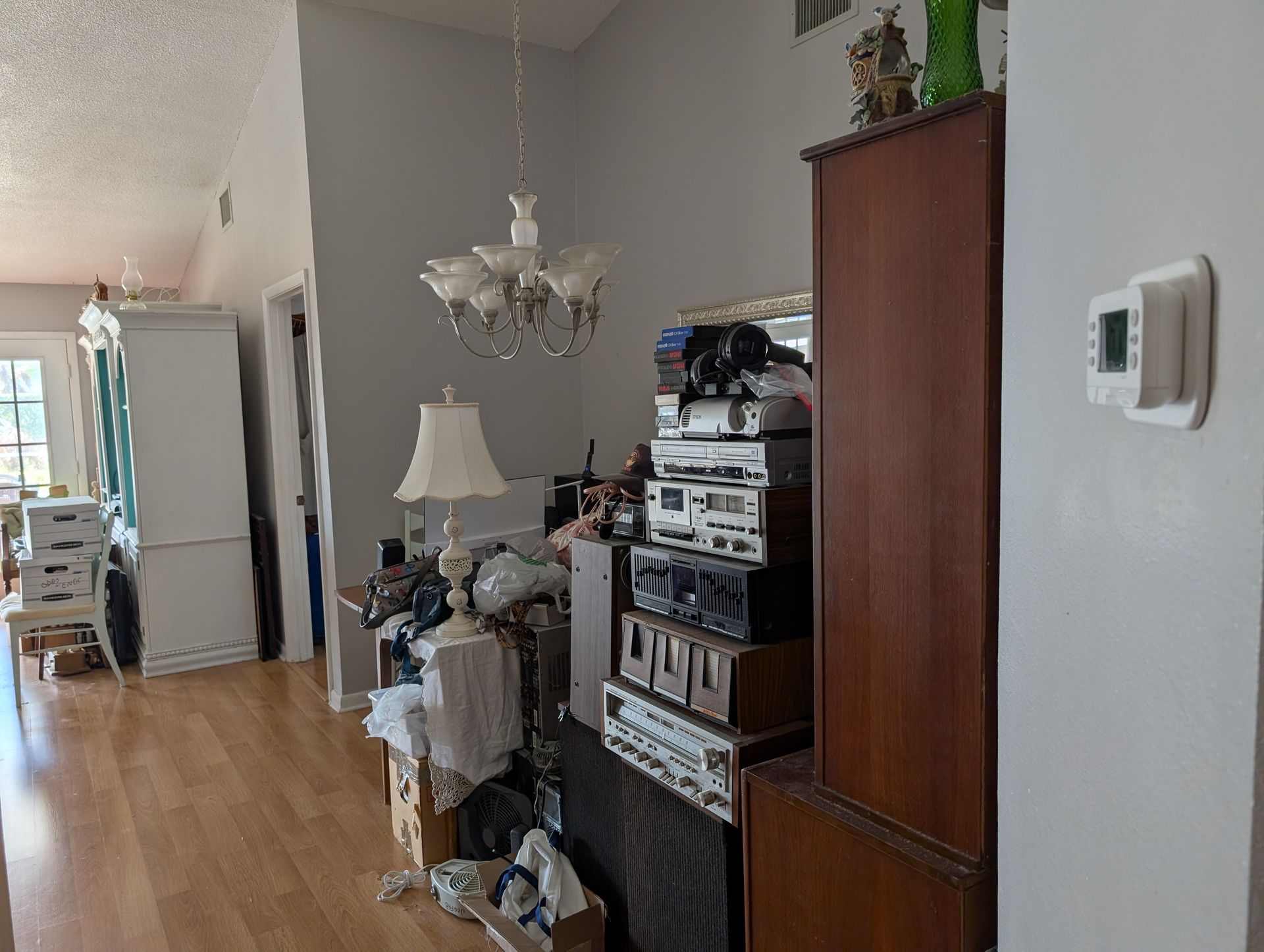 Hallway with cluttered furniture, a chandelier, and a thermostat on the wall.