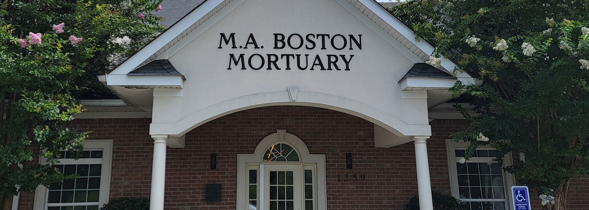 M.A. Boston Mortuary sign above a brick building entrance with white archway.