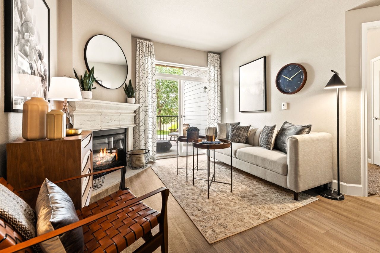 Living room with beige sofa, fireplace, round mirror, and sliding balcony door.