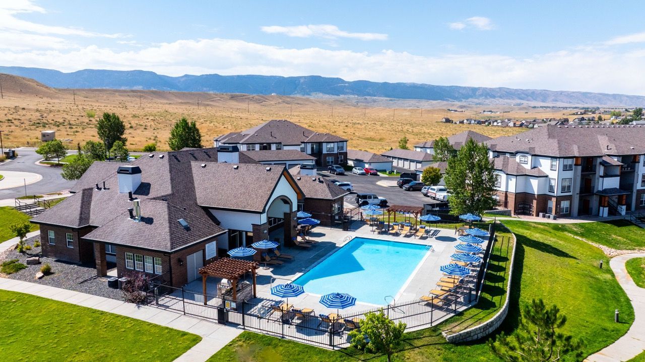 Aerial view of a community pool with lounge chairs and blue umbrellas, surrounded by apartment buildings  at The Preserve at Greenway Park.