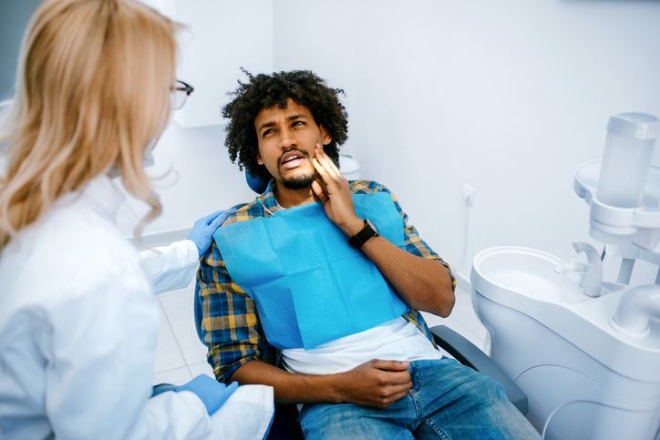 A woman is sitting in a dental chair while a dentist examines her teeth