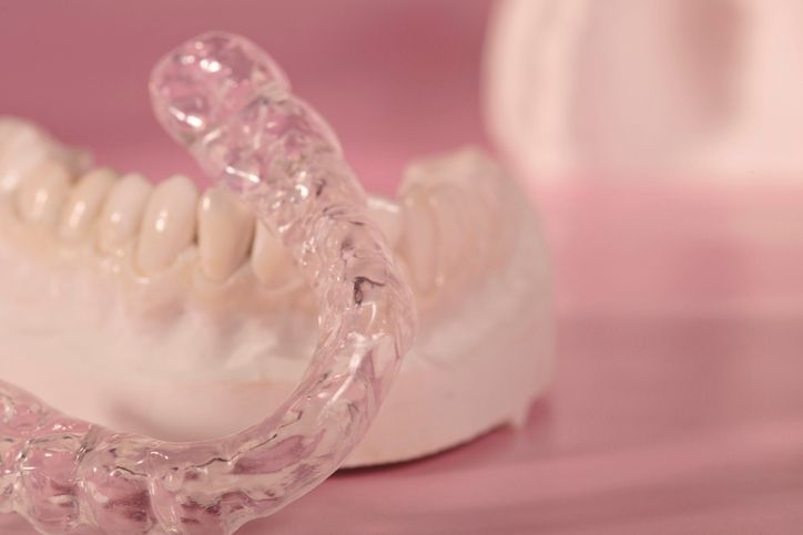 A woman is holding a clear mouth guard in her hand