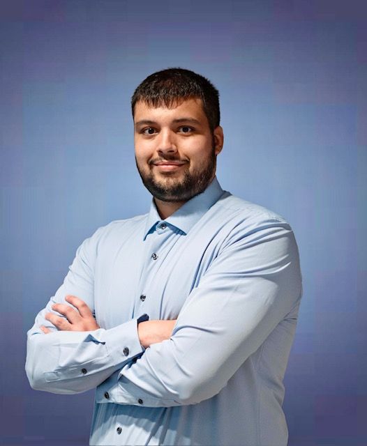 A man with a beard is posing for a picture with his arms crossed.
