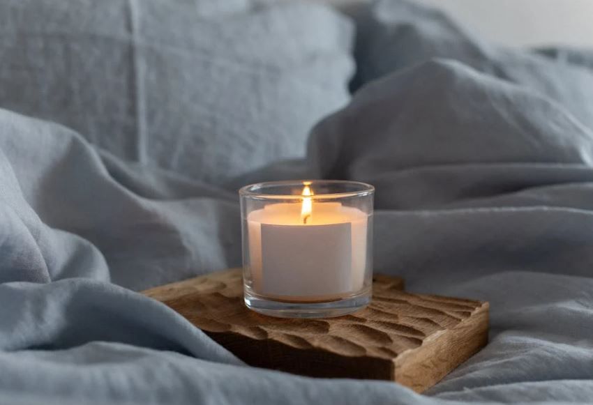 Lit candle on cozy bedding, support for grieving wives, cremation services Bonaire, GA