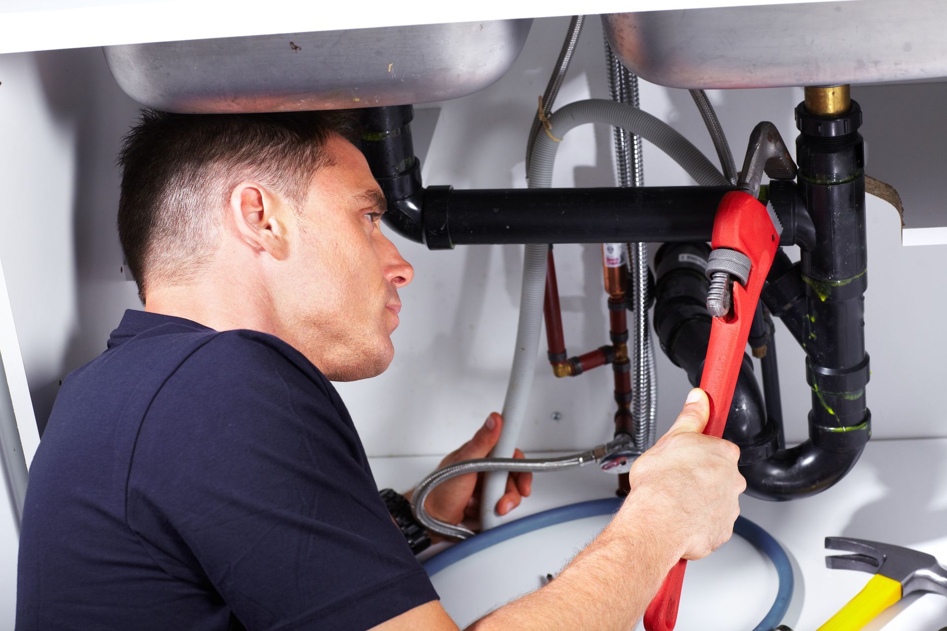 Licensed commercial plumber fixing sink pipes with wrench.