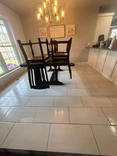 Dining room with white tiled floor, black chairs, wall art, and large window light.